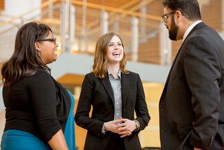 Three students in business attire talking